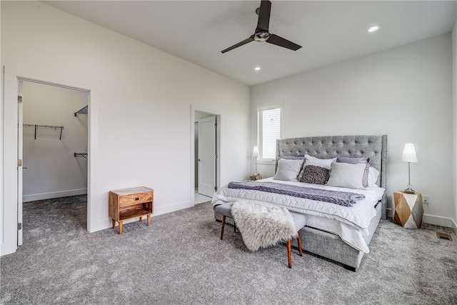 bedroom featuring a spacious closet, a closet, carpet, and ceiling fan