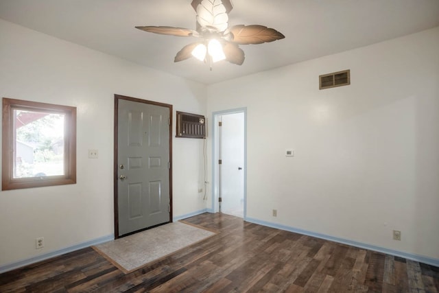 unfurnished bedroom with ceiling fan, dark wood-type flooring, and an AC wall unit