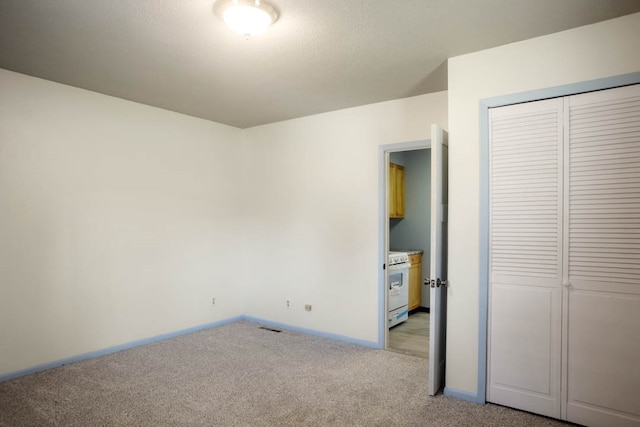 unfurnished bedroom featuring light carpet and a closet