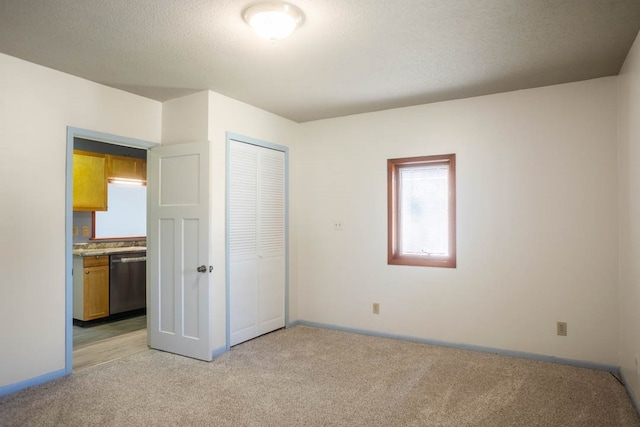 unfurnished bedroom with light carpet, a closet, and a textured ceiling