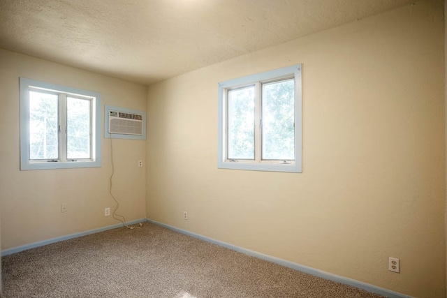 empty room featuring carpet floors, a textured ceiling, and a wall mounted AC