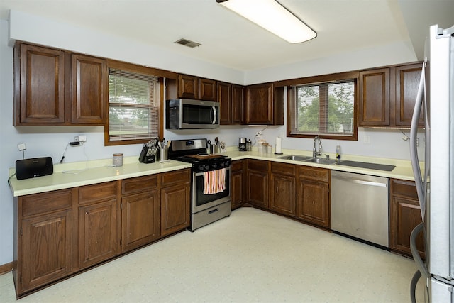 kitchen featuring appliances with stainless steel finishes, dark brown cabinetry, and sink