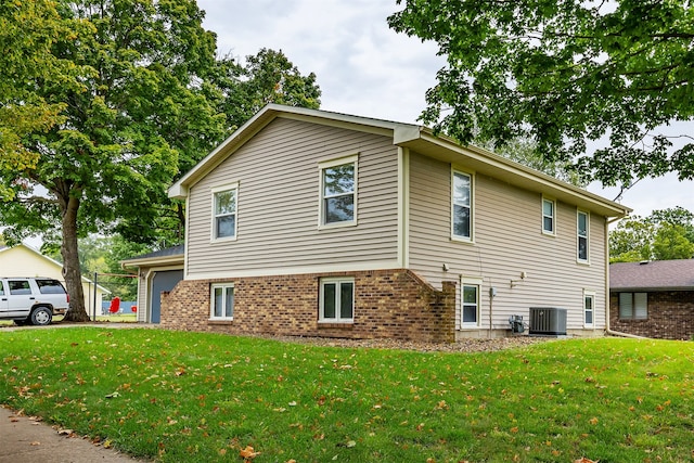 view of side of property with a lawn, a garage, and central AC