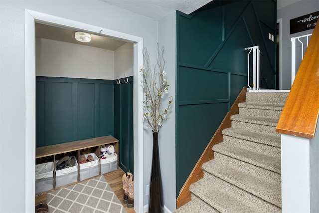 stairway with a textured ceiling and hardwood / wood-style floors