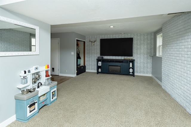 carpeted living room with a healthy amount of sunlight, brick wall, and a fireplace