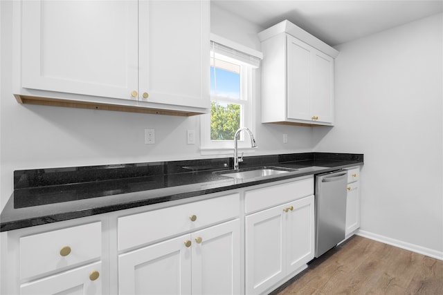 kitchen featuring sink, white cabinetry, dark stone counters, stainless steel dishwasher, and light hardwood / wood-style flooring