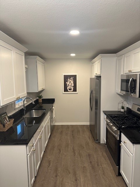 kitchen featuring sink, a textured ceiling, dark hardwood / wood-style flooring, white cabinetry, and stainless steel appliances