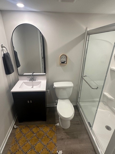 bathroom with a shower with door, vanity, toilet, and wood-type flooring