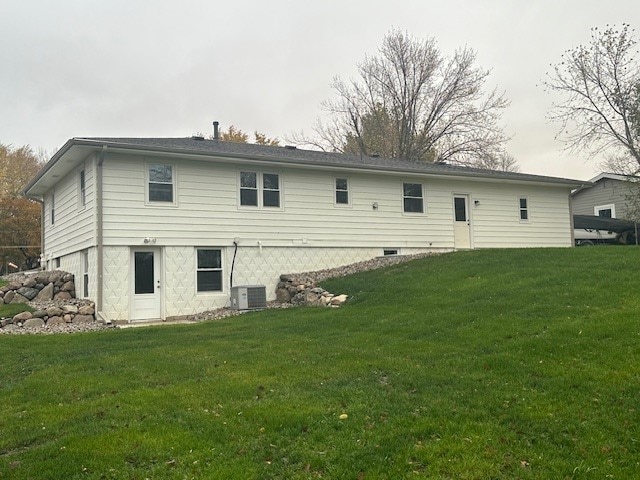 rear view of house with central air condition unit and a yard