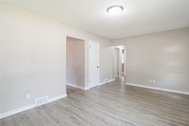 spare room featuring baseboards, visible vents, and light wood finished floors