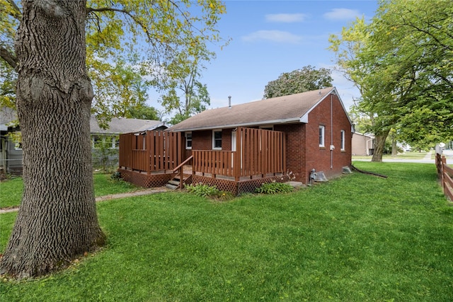 rear view of property with brick siding, a lawn, and a wooden deck