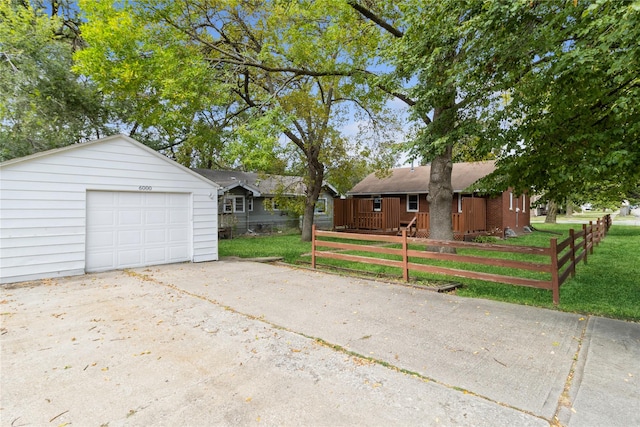 exterior space with concrete driveway, a front lawn, an outdoor structure, and fence