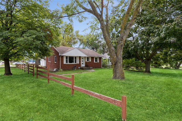 view of front of house with brick siding, a front lawn, and fence