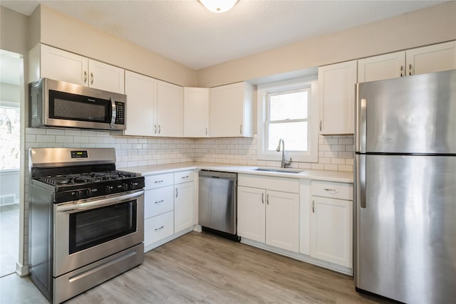 kitchen with light hardwood / wood-style floors, white cabinetry, sink, and stainless steel appliances