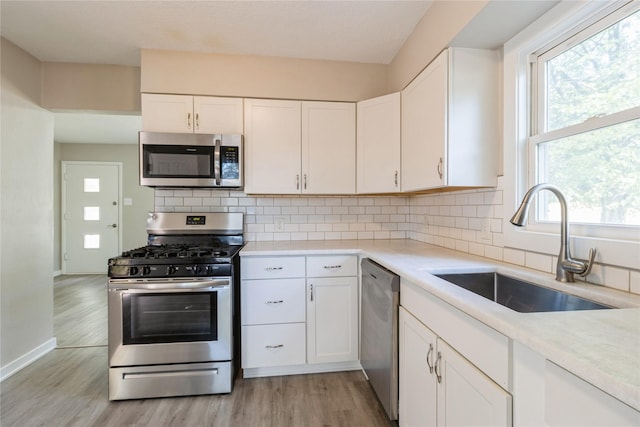 kitchen featuring appliances with stainless steel finishes, white cabinets, light countertops, and a sink