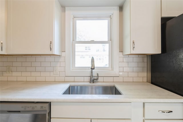 kitchen with tasteful backsplash, light countertops, white cabinetry, a sink, and dishwasher