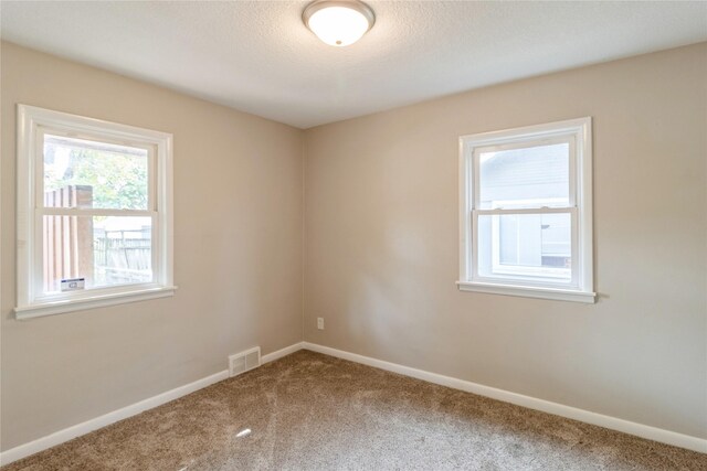 carpeted empty room featuring a textured ceiling