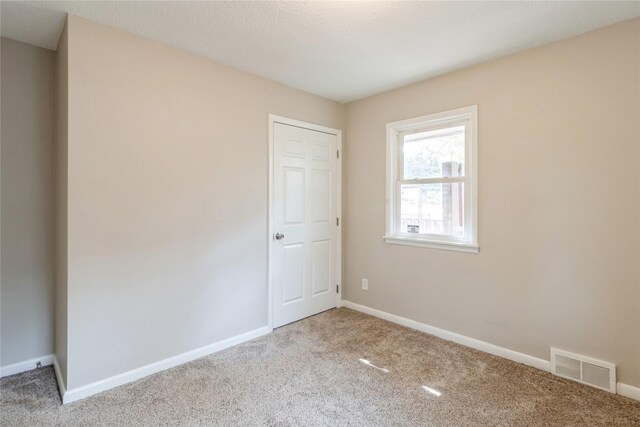 unfurnished room with a textured ceiling and carpet flooring