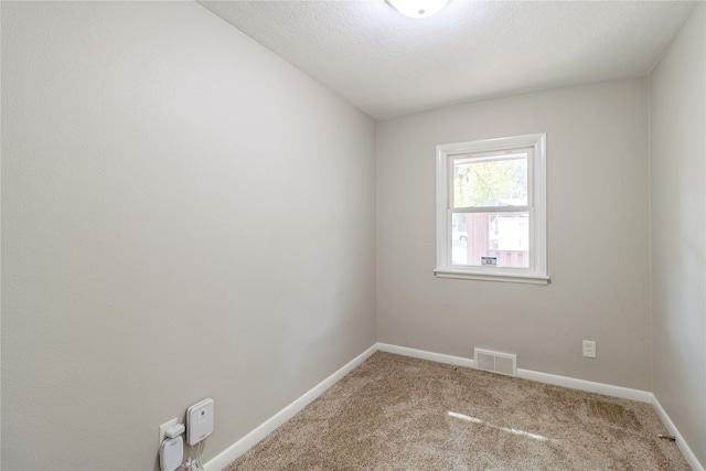 carpeted empty room with baseboards, visible vents, and a textured ceiling