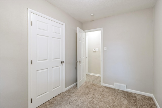 unfurnished bedroom with baseboards, visible vents, and light colored carpet