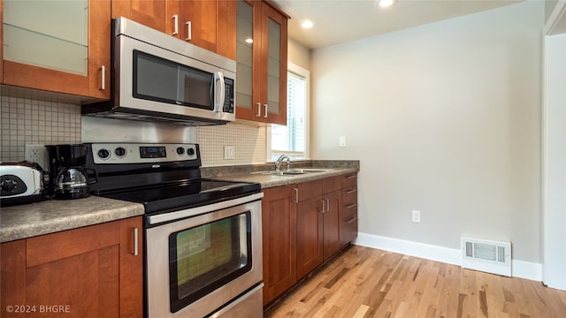 kitchen featuring tasteful backsplash, sink, light hardwood / wood-style floors, and appliances with stainless steel finishes