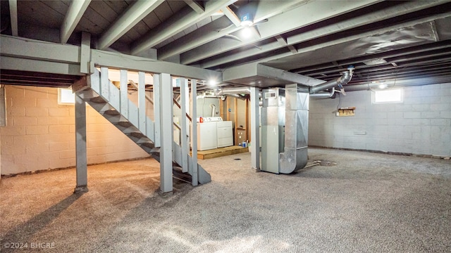 basement featuring washing machine and clothes dryer, heating unit, and carpet flooring