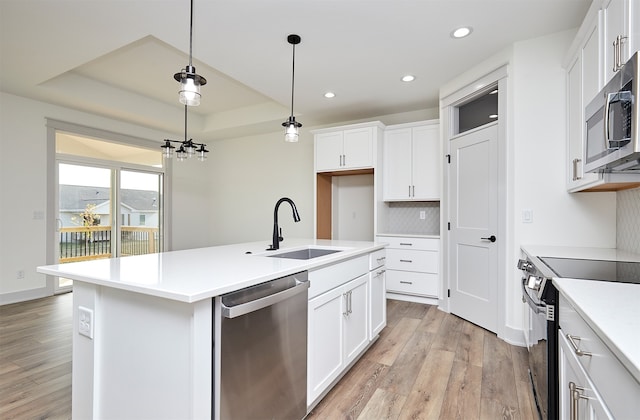 kitchen featuring white cabinets, a center island with sink, appliances with stainless steel finishes, and sink