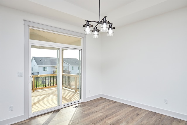 unfurnished dining area featuring light hardwood / wood-style floors and a chandelier