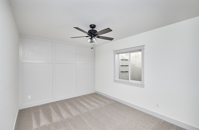 spare room with ceiling fan, light colored carpet, and a textured ceiling