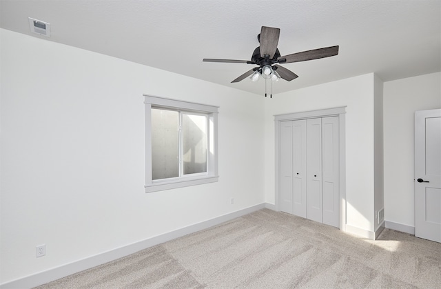 unfurnished bedroom featuring a textured ceiling, ceiling fan, a closet, and light colored carpet