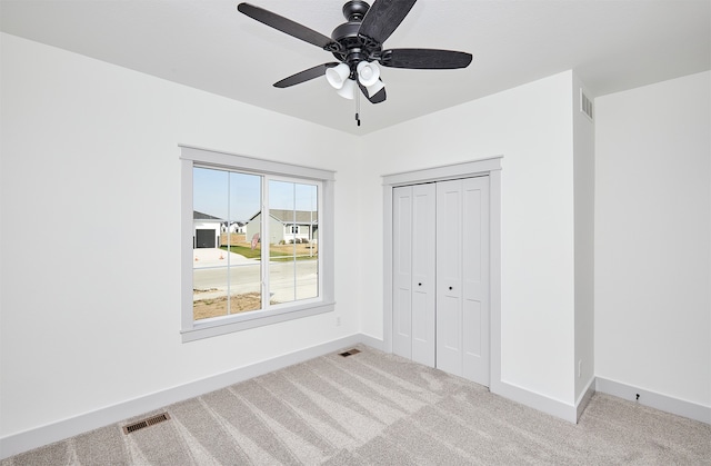 unfurnished bedroom with light carpet, ceiling fan, and a closet