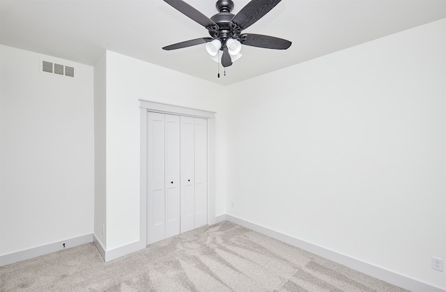 unfurnished bedroom featuring light carpet, a closet, and ceiling fan