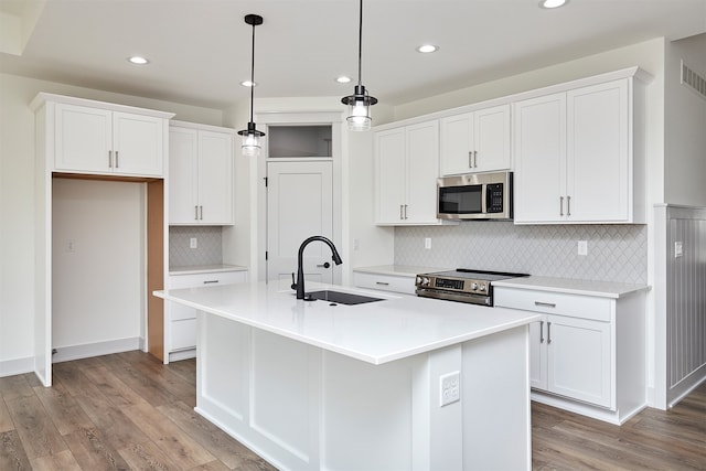 kitchen featuring light hardwood / wood-style flooring, a center island with sink, sink, appliances with stainless steel finishes, and white cabinetry