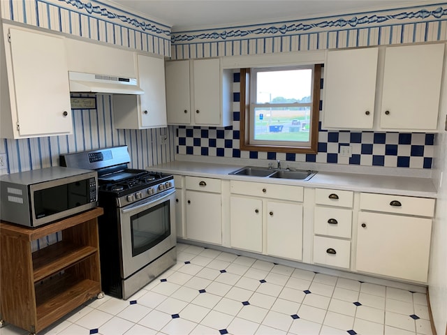 kitchen featuring ventilation hood, sink, white cabinets, decorative backsplash, and appliances with stainless steel finishes