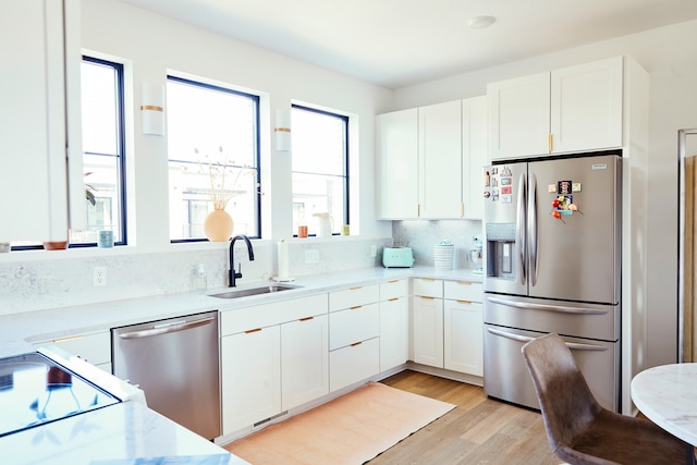 kitchen featuring white cabinets, stainless steel appliances, light wood-type flooring, and sink