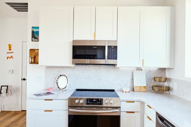 kitchen with light hardwood / wood-style flooring, white cabinetry, and appliances with stainless steel finishes