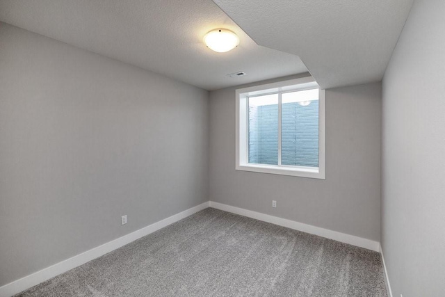 spare room featuring carpet flooring and a textured ceiling