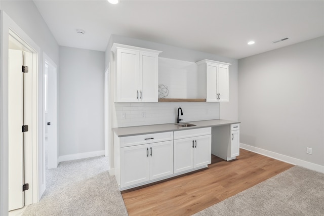 kitchen featuring sink, white cabinets, light hardwood / wood-style floors, and decorative backsplash