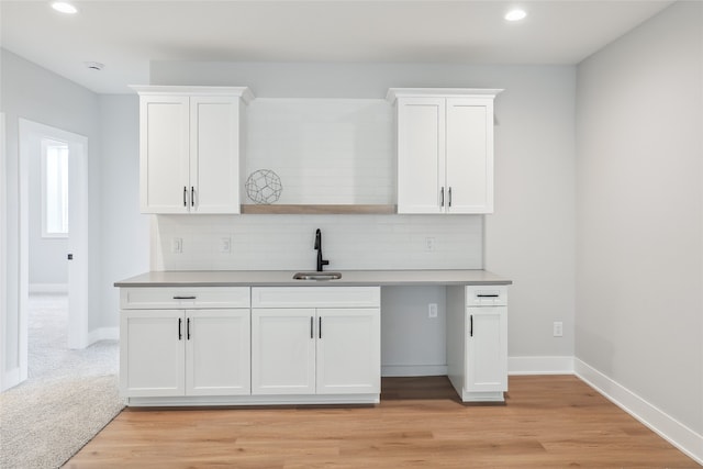 kitchen featuring light hardwood / wood-style floors, sink, decorative backsplash, and white cabinets