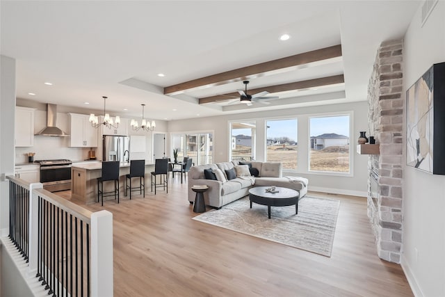 living room featuring ceiling fan with notable chandelier, beam ceiling, and light hardwood / wood-style flooring