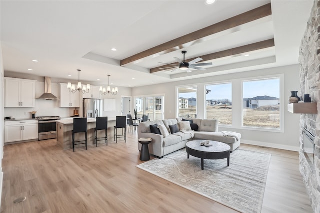 living room featuring a fireplace, beam ceiling, ceiling fan with notable chandelier, and light hardwood / wood-style flooring