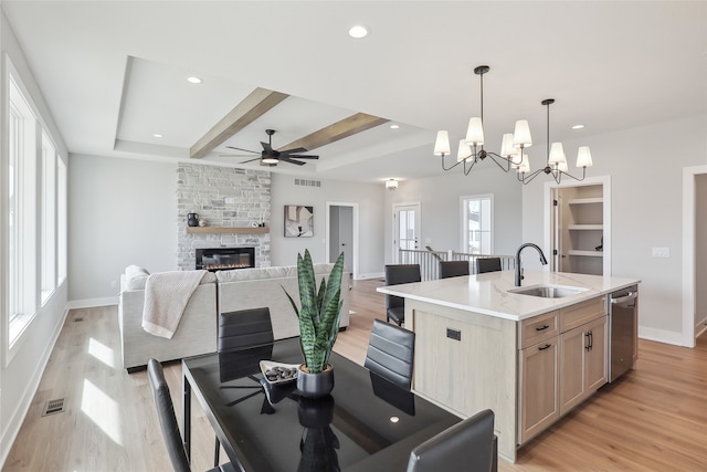 kitchen with sink, light brown cabinets, dishwasher, an island with sink, and pendant lighting