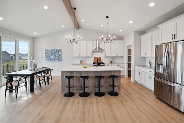 kitchen featuring white cabinetry, stainless steel fridge, a center island with sink, and light wood-type flooring