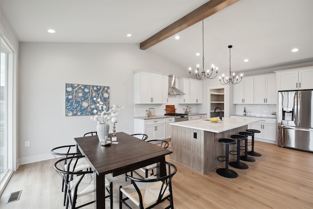 kitchen with wall chimney exhaust hood, an island with sink, light hardwood / wood-style flooring, stainless steel appliances, and white cabinets