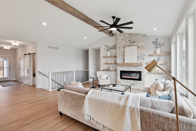 living room featuring lofted ceiling with beams, light wood-type flooring, and a barn door