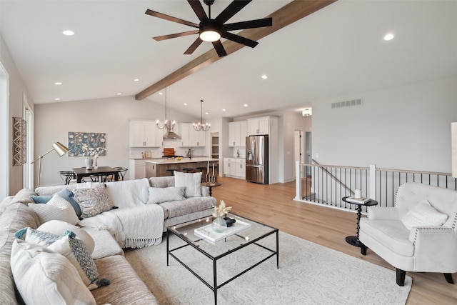 living room with sink, lofted ceiling with beams, light hardwood / wood-style flooring, and ceiling fan with notable chandelier