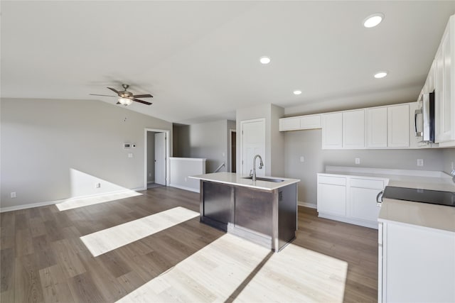 kitchen with white cabinets, sink, dark hardwood / wood-style floors, a kitchen island with sink, and vaulted ceiling