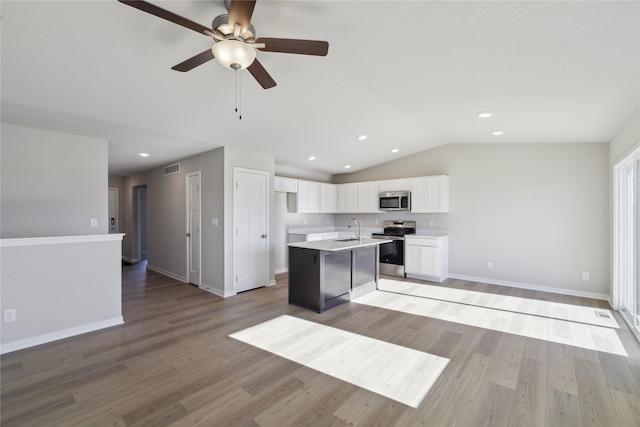 kitchen with white cabinets, stainless steel appliances, an island with sink, sink, and light wood-type flooring