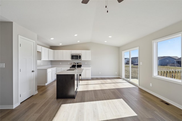 2105 White Oak Ln, Granger, IA 50109 - kitchen featuring stainless steel microwave, a kitchen island with sink, lofted ceiling, light wood finished floors, and white cabinets