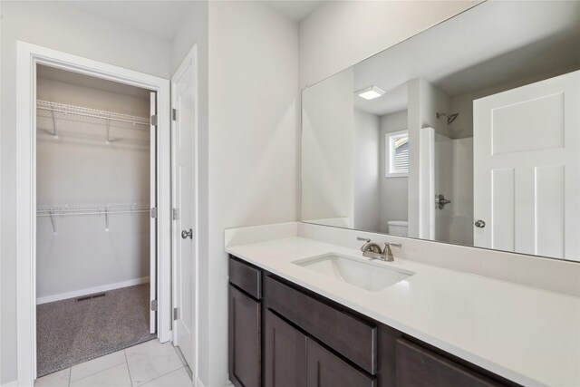 bathroom featuring vanity, toilet, walk in shower, and tile patterned floors